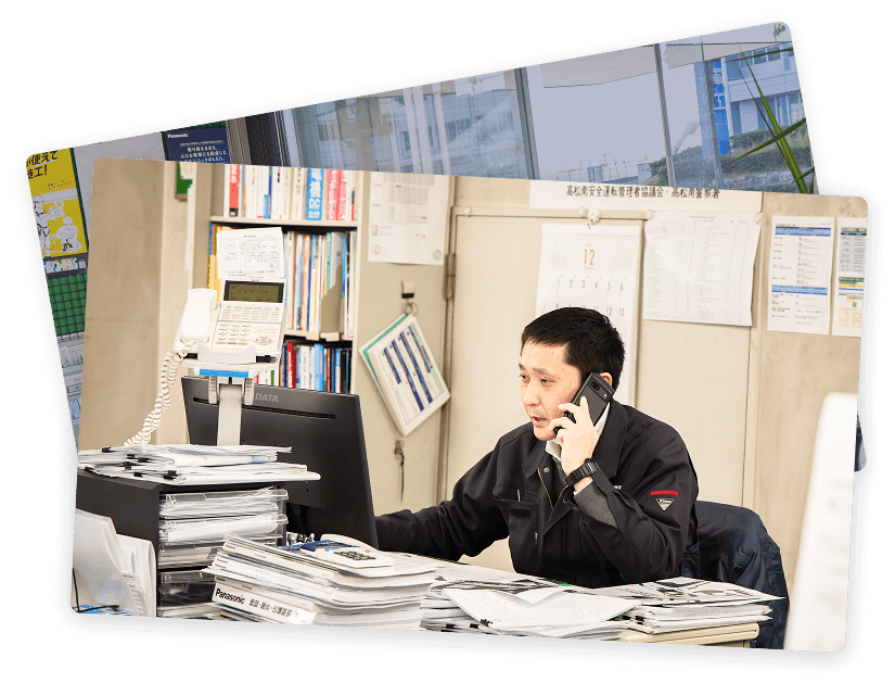 オフィスで電話対応をしながらパソコン作業を行う社員の様子