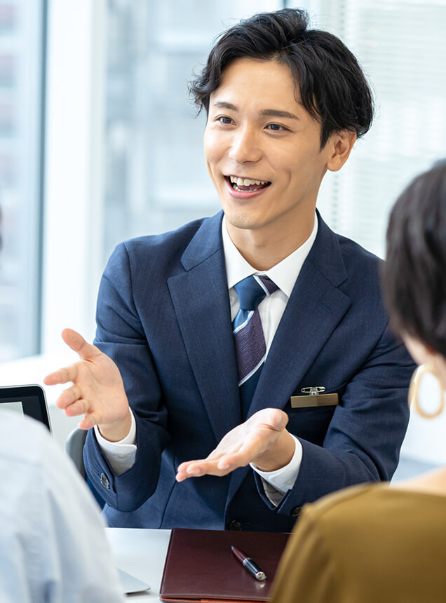 商談席で笑顔で打ち合わせを行う男性社員の様子