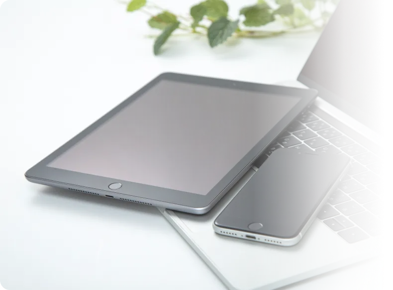 ノートパソコンとタブレット、スマートフォンを使ったIT機器イメージ