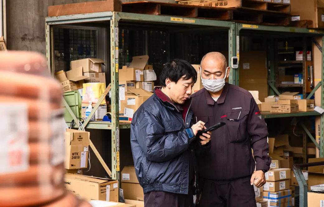 倉庫内でスマホを見ながら確認をする社員の様子