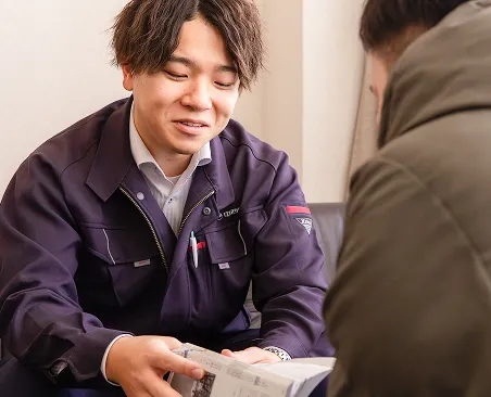 カタログを見せながらお客様に商品説明を行う社員