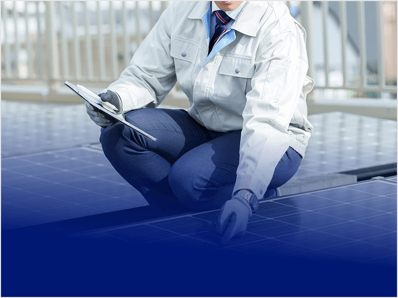 屋上の太陽光パネルを点検する作業員